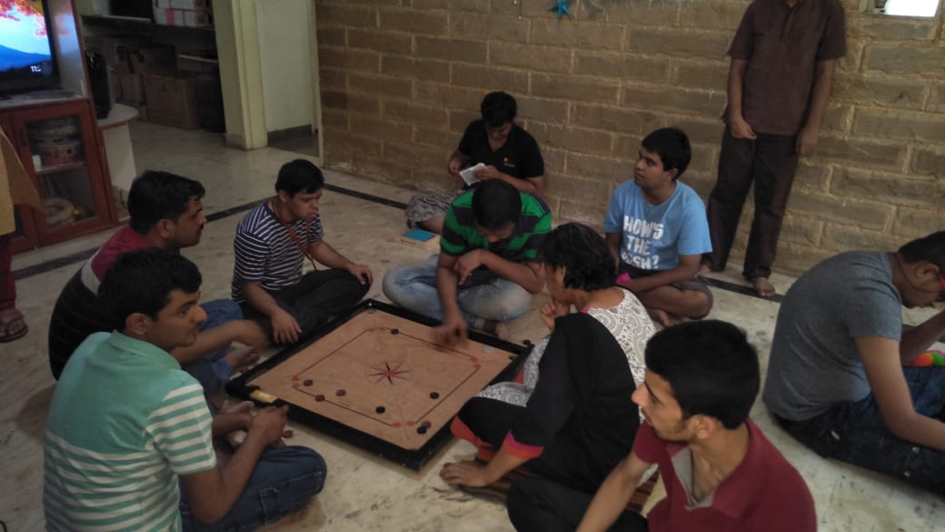 Participants gather around a carrom board for a lively indoor game session