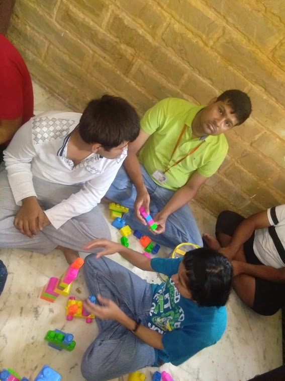 Participants and a staff member sit together on the floor building with colourful interlocking blocks