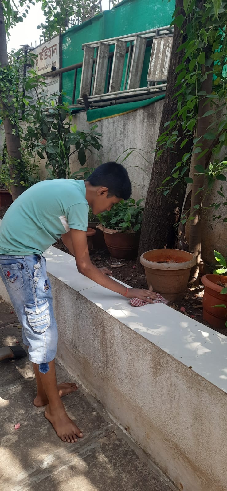 A participant wipes down an outdoor tiled ledge with a cloth, practising cleaning and household upkeep
