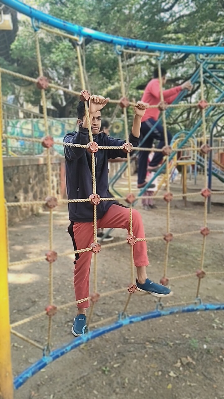 Young man climbing rope net at playground